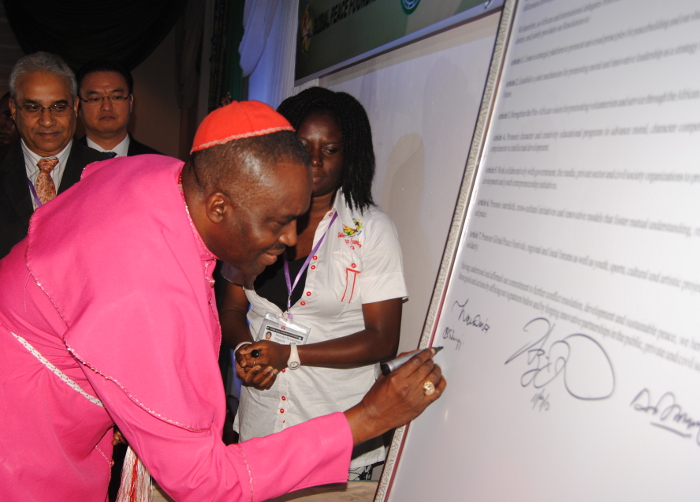 El Obispo Sunday Onuoha suma su firma a la Declaración de Abuya en el cierre de CPLG 2013. Los delegados internacionales de más de 20 naciones se comprometen a "Crear una plataforma estratégica para promover principios universales para la construcción de paz y nuestros valores comunes como Una Familia Bajo Dios."