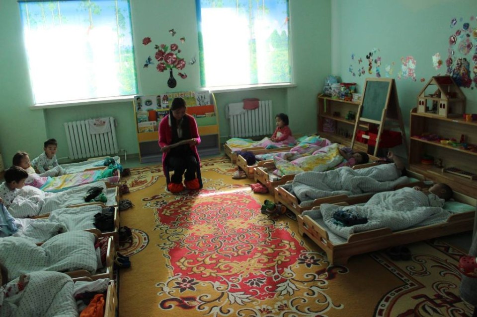 Una estudiante universitaria voluntaria lee a los estudiantes de guardería antes de la siesta en Mongolia